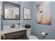 Charming powder room with blue walls, framed artwork, and a vanity with a dark wood finish at 545 Ashvale Overlook, Alpharetta, GA 30005