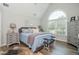 Cozy bedroom with blue bedding, gray furniture, and a large arched window for natural light at 545 Ashvale Overlook, Alpharetta, GA 30005