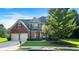 Charming two-story brick home featuring lush landscaping, a two-car garage, and a welcoming front porch at 1496 Clarecastle Ln, Buford, GA 30519