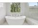 Contemporary freestanding tub with marble tile surround with bronze fixtures near large window at 3205 Bold Springs Rd, Dacula, GA 30019