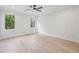 Bright bedroom featuring hardwood floors, a ceiling fan, and multiple windows overlooking a tree lined lot at 3205 Bold Springs Rd, Dacula, GA 30019