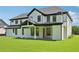 Expansive backyard with lush grass showcasing a modern, white brick home with a covered patio at 3205 Bold Springs Rd, Dacula, GA 30019