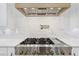 Close-up of a modern gas range with custom hood and marble backsplash in a well-appointed kitchen at 3205 Bold Springs Rd, Dacula, GA 30019