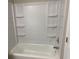Bathroom featuring a white shower and tub combo with built in shelves at 646 Lakes Cir, Lithonia, GA 30058