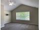 Spacious bedroom features vaulted ceilings, a ceiling fan, gray carpet, and a large window at 646 Lakes Cir, Lithonia, GA 30058