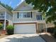 Two-story home with a well-manicured lawn, an attached garage, and mature trees at 646 Lakes Cir, Lithonia, GA 30058