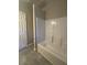 Bright bathroom featuring a white tiled tub and gray tile flooring at 2103 River Rd, Ellenwood, GA 30294