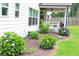 Well-manicured backyard featuring hydrangea bushes and a covered porch with swing seating at 688 Harmony Rd, Temple, GA 30179