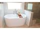 Bright bathroom with a standalone tub next to a glass enclosed shower featuring vertical patterned tiling at 688 Harmony Rd, Temple, GA 30179