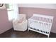 Bedroom features hardwood floors, a glider chair with a pillow, a white baby crib, and natural light at 688 Harmony Rd, Temple, GA 30179