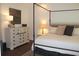 Bright bedroom features a four poster bed, an ornate dresser with a decorative lamp, and hardwood floors at 688 Harmony Rd, Temple, GA 30179