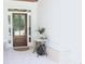 Inviting front porch with a wood door, white brick flooring, and a decorative sewing machine table at 688 Harmony Rd, Temple, GA 30179