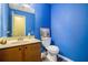 Bright blue half bathroom with vanity, toilet, mirror, and modern fixtures at 1919 Cheatham Woods Sw Dr, Marietta, GA 30008