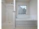 Bright bathroom features a separate shower and soaking tub under a large window at 148 Barrington Pkwy, Stockbridge, GA 30281