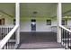 Close-up of covered front porch with black railings, stylish white supports, and wooden shutters at 2122 Browntown Rd, Rockmart, GA 30153