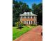 Charming two-story brick home with a manicured lawn, mature trees, and a red brick driveway at 3201 Palisades Se Ct, Marietta, GA 30067