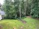 Overgrown backyard with green lawn and mature trees, partially fenced at 8130 Estee Dr, Cumming, GA 30028