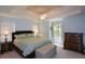 Bedroom featuring tray ceiling, large bed, upholstered bench, and dresser at 8130 Estee Dr, Cumming, GA 30028