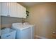 Laundry room features white cabinets, washer, dryer, sink, and wall shelving at 8130 Estee Dr, Cumming, GA 30028