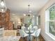 Open-concept dining area with glass table, modern lighting, and exposed brick, seamlessly flows into the living room at 1272 Hardee Ne St, Atlanta, GA 30307