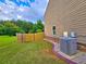 A green backyard with a wooden fence, a two-story home, and a large air conditioning unit at 171 Shaker Hollow Drive Dr, Mcdonough, GA 30253