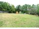 Spacious backyard with a wooden fence, mature trees, greenhouse, and shed, offering a private and functional outdoor space at 3824 Smith Creek Ct, Buford, GA 30519