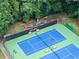 This aerial shot showcases blue and green tennis courts next to a playground area with mature trees at 4249 Arbor Club Dr, Marietta, GA 30066