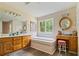 A bathroom with double sink vanity, large mirror, soaking tub, and wood-look floors at 145 Deep Step Rd, Covington, GA 30014