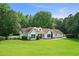 Charming white home boasts a lush green lawn, mature trees, and inviting curb appeal at 145 Deep Step Rd, Covington, GA 30014