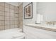 A clean, well-lit bathroom featuring tiled walls, a bathtub with shower, and a vanity with a granite countertop at 541 Fundao Ln, Lawrenceville, GA 30046