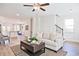 Bright living room featuring wood floors, a ceiling fan, and views into the kitchen and dining areas at 541 Fundao Ln, Lawrenceville, GA 30046