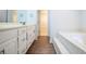 Bathroom featuring wood look floors, a tiled tub, and a dual sink vanity at 6203 Crestview Drive Southeast Se Dr, Covington, GA 30014