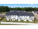 Aerial view of the back of townhomes with well-kept lawns and mature trees in the distance at 225 Silver Moon Dr, Loganville, GA 30052