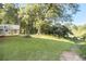 Large green backyard with trees and a glimpse of a lake in the distance on a sunny day at 1077 Mainstreet Valley Dr, Stone Mountain, GA 30088