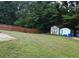 View of a fenced backyard with a storage shed and a level, green lawn at 20 Bacchus Dr, Lawrenceville, GA 30045