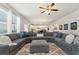 Spacious living room with a large sectional sofa, a ceiling fan, and dark hardwood floors at 253 Orchard Trl, Holly Springs, GA 30115