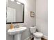 Bright powder room featuring a pedestal sink, modern fixtures, and decorative wall art at 253 Orchard Trl, Holly Springs, GA 30115