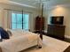 Spacious main bedroom featuring a four-poster bed, tray ceiling, and a large window with serene views at 5085 Johns Creek Ct, Johns Creek, GA 30022