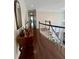 Upstairs hallway with hardwood floors, a dark wood railing and a view of the entry at 5085 Johns Creek Ct, Johns Creek, GA 30022