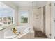 Bright bathroom featuring a soaking tub under a window and a glass-enclosed shower at 479 Rising Sun Path, Lawrenceville, GA 30043