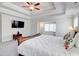 A bright bedroom with a tray ceiling features a mounted TV, ceiling fan, and stylish decor at 774 Phil Haven Ln, Kennesaw, GA 30152
