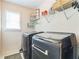 Modern laundry room featuring a front-loading washer and dryer set, and wire shelving above, near a window at 840 Milton Oaks Dr, Johns Creek, GA 30022