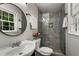 Modern bathroom featuring a glass-enclosed shower, round mirror, and a sleek vanity at 2694 Hickory Valley Dr, Snellville, GA 30078