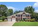Charming brick home with a manicured lawn, mature trees, a two-car garage, and classic architectural details at 3055 Dogwood Hollow Ln, Lawrenceville, GA 30043