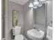 Bathroom with a corner sink, white toilet, accent mirror, and modern lighting fixtures at 2994 Baker Ridge Nw Dr, Atlanta, GA 30318