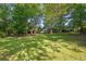 Spacious backyard with mature trees providing shade, and a view of the house in the distance at 6674 Cowan Mill Rd, Winston, GA 30187