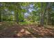 Backyard view with mature trees, lush greenery, and a glimpse of the main residence in the background at 6674 Cowan Mill Rd, Winston, GA 30187