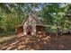 Small outbuilding with stacked wood and a covered area in a wooded, shady area at 6674 Cowan Mill Rd, Winston, GA 30187