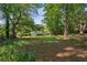 Lush backyard view with a gentle slope, mature trees, and partial view of the house at 6674 Cowan Mill Rd, Winston, GA 30187