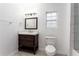 Bright bathroom featuring a dark wood vanity, granite countertop, framed mirror, and modern lighting, alongside white fixtures at 83 Ormond Se St, Atlanta, GA 30315